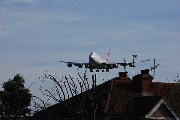 A plane flying close to houses.